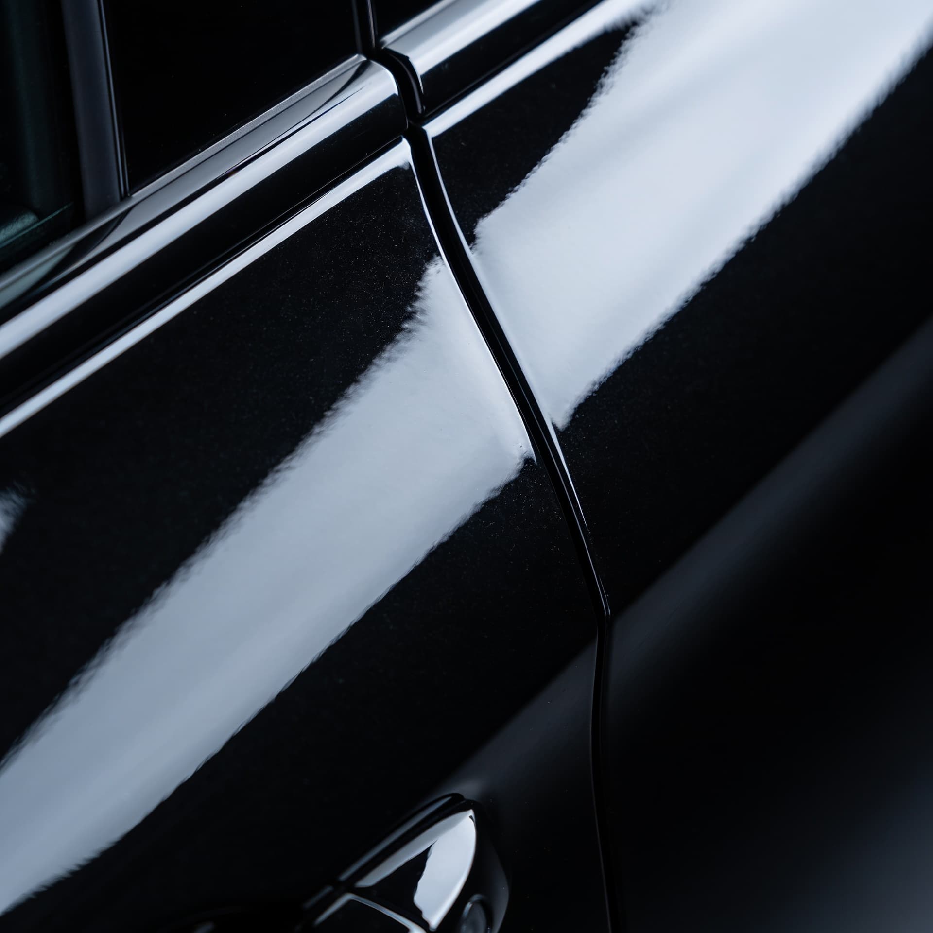 Macro of a spotless black door panel reflecting cool ambient light